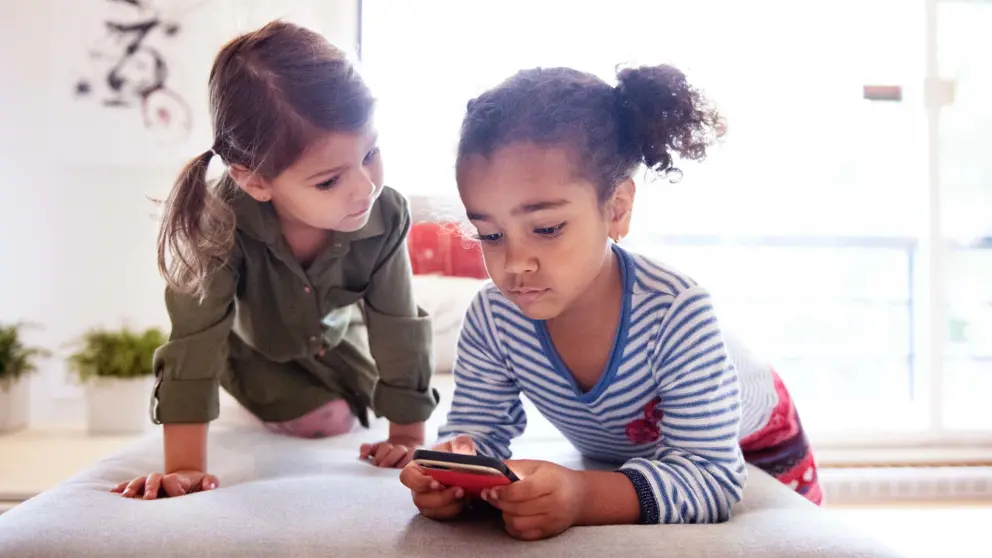 Deux enfants en train d’utiliser un téléphone intelligent 