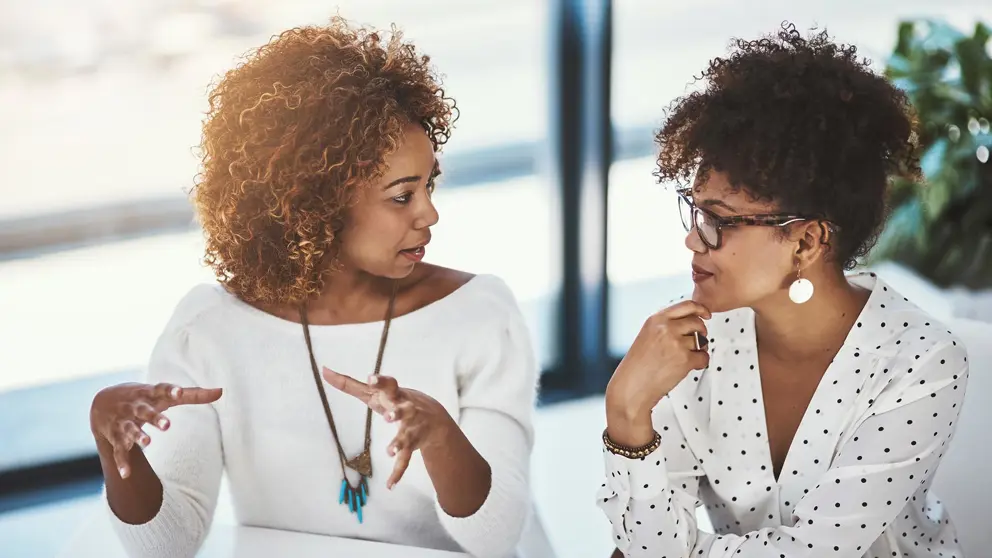  Deux femmes professionnelles se parlent assis dans une salle de conférence