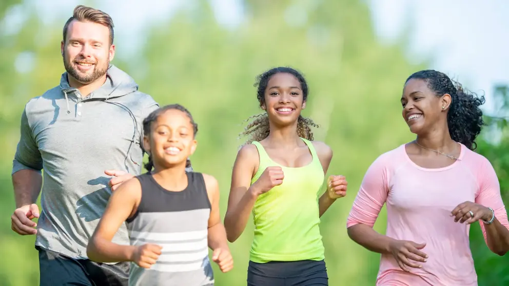 Une famille de quatre fait du jogging; deux enfants courent au milieu, avec leurs parents de chaque côté.