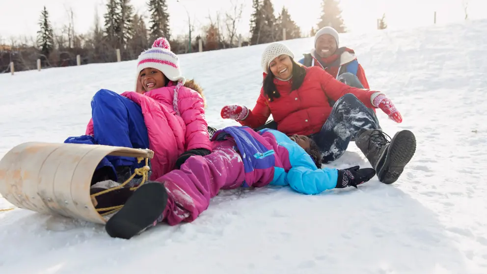  Famille faisant de la luge sur une colline enneigée