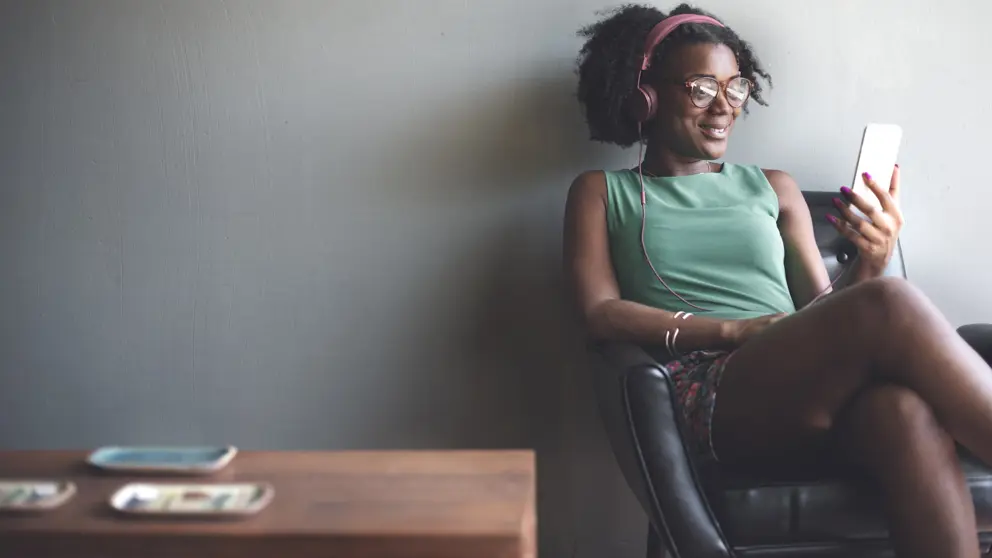 Femme de détente dans un fauteuil tout en écoutant de la musique sur l'iPod