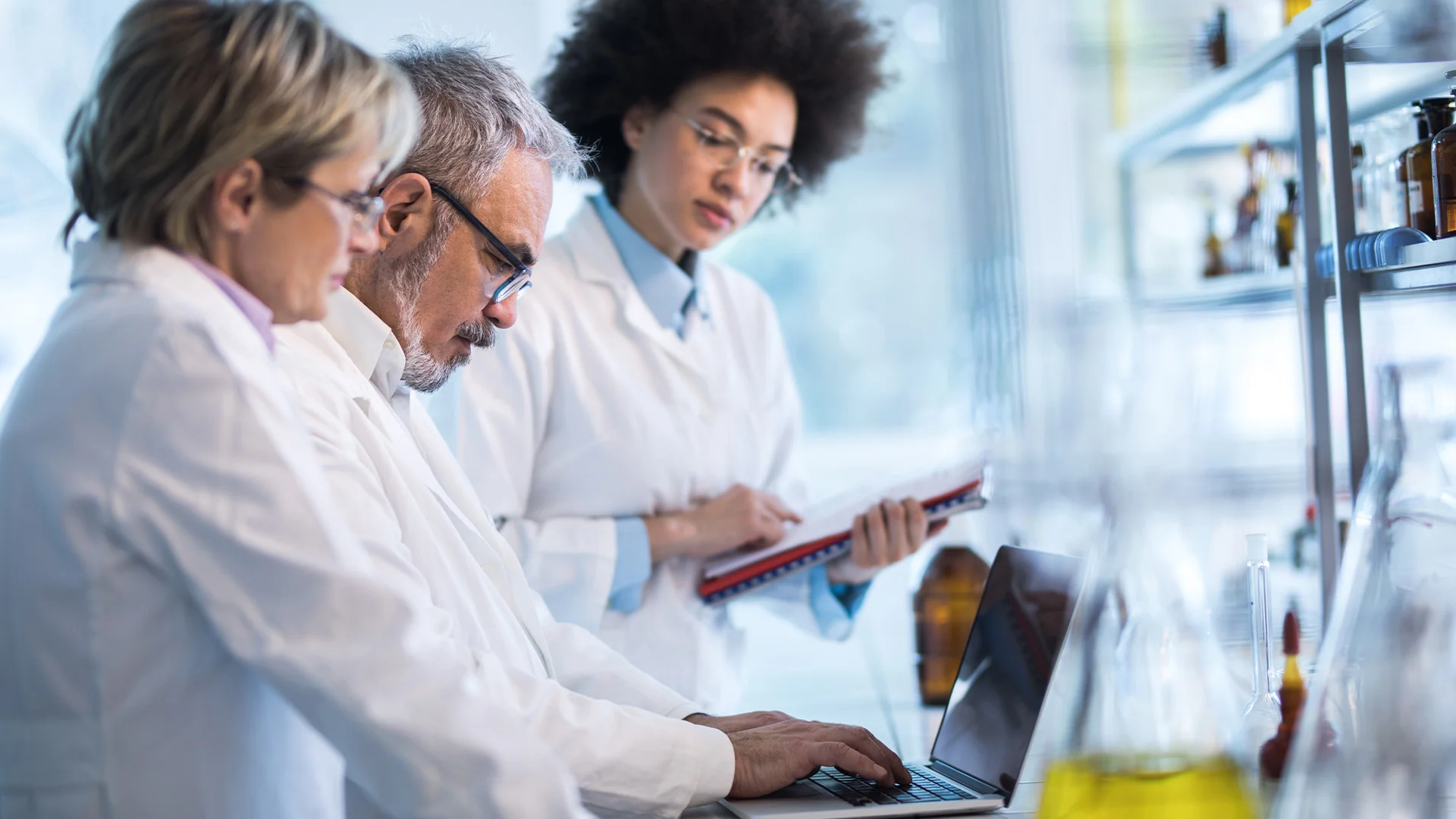 Un chercheur de laboratoire sourit à la caméra tout en tenant une tablette.