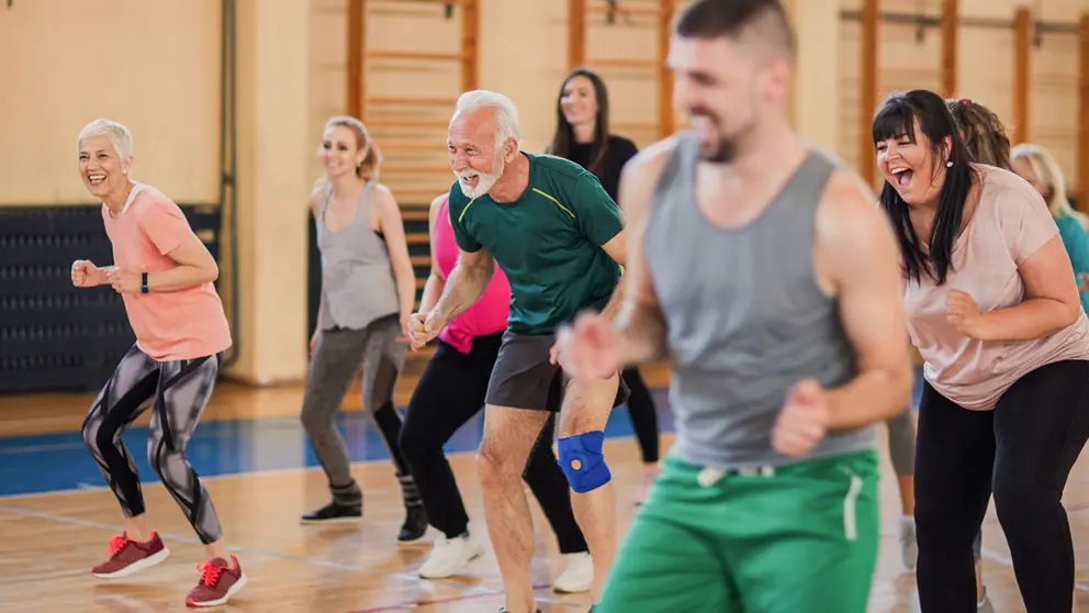 Groupe souriant et heureux de personnes dansant au gymnase