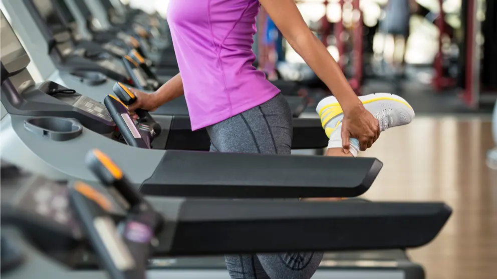 Femme qui s'étend ses jambes sur le tapis roulant